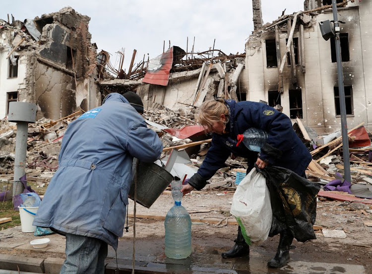 Local residents draw water from a well near the building of a theatre destroyed in the course of Ukraine-Russia conflict in the southern port city of Mariupol Ukraine April 3, 2022. REUTERS/Alexander Ermochenko