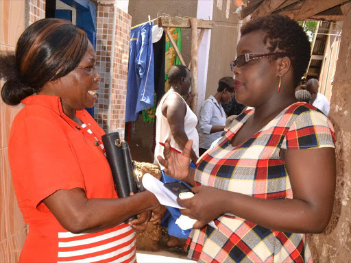 Teresiah Achieng 43 years old (in red) is a retired Traditional birth attendant (TBA) from Kisumu Ndogo village within Maweni slums of Mombasa share a light moment with DSW programs officer Judy Mboku.Achieng is now a trained Champion on issues of safe motherhood delivery.PHOTO Mkamburi Mwawasi