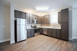 Kitchen with dark brown cabinets, stainless steel appliances, granite countertops, brown and tan backsplash, dark wood floors