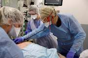 Medical workers, wearing protective gear, work in the intensive care unit (ICU) where patients suffering from the coronavirus disease (Covid-19) are treated at Cambrai hospital, France, April 1, 2021.   