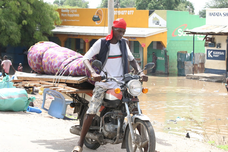 A resident of Mororo carries his belongings on a motorbike following floods in the area.