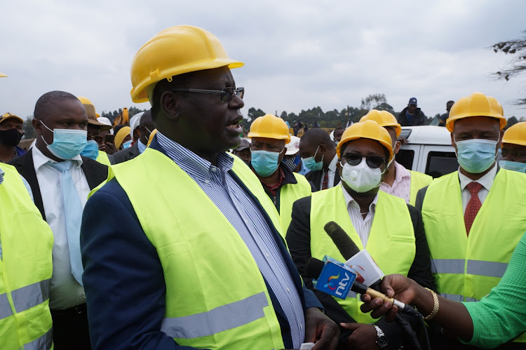 Kiambu Governor James Nyoro speaks to journalists as Urban Development PS Charles Hinga (C) looks on at Dagorreti market on Wednesday.