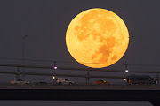 Cars drive across the July 15 Martyrs Bridge (Bosphorus Bridge) as the rare Super Blue Moon sets behind on August 31, 2023 in Istanbul, Turkey. The rare supermoon is an occurrence which won't happen again until 2037. The term 