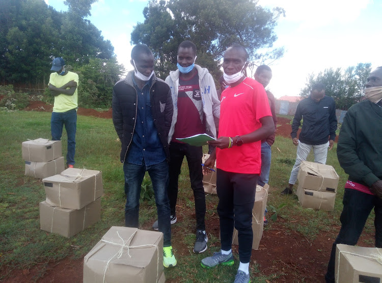 Eliud Kipchoge in red while donating foodstuffs in Kapsabet