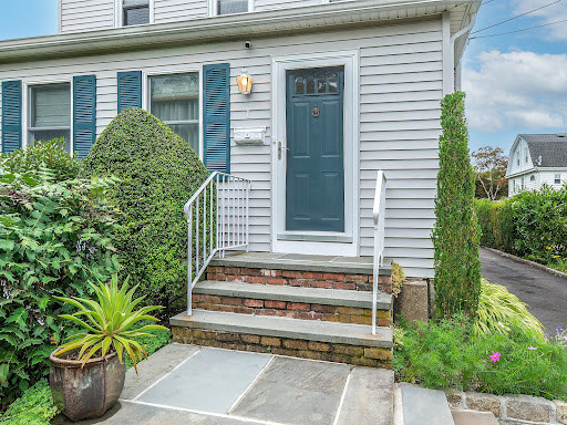 House front with blue door and garden in this luxury property for sale in Glen Cove ($799,000)
