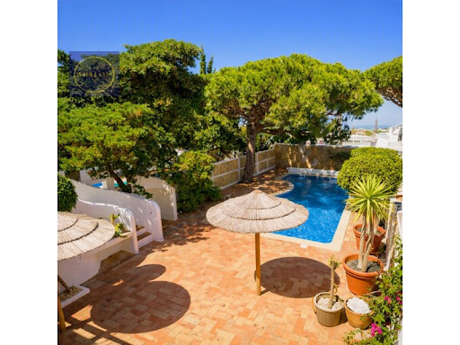 Outdoor swimming pool with straw parasols in this luxury property for sale in Almancil ($1,977,215 - 134 m²)