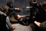 Women fan a model as she lies on the ground after having suffered from dizziness before the start of an event to show off designer traditional mantilla costumes in Seville, Spain. 