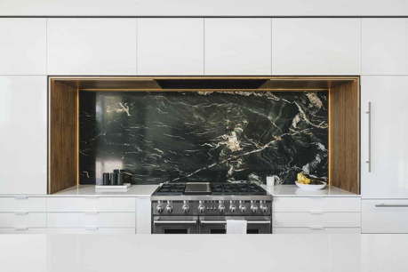 image of a luxury kitchen with marble backsplash, white cabinets, and a high tech stove