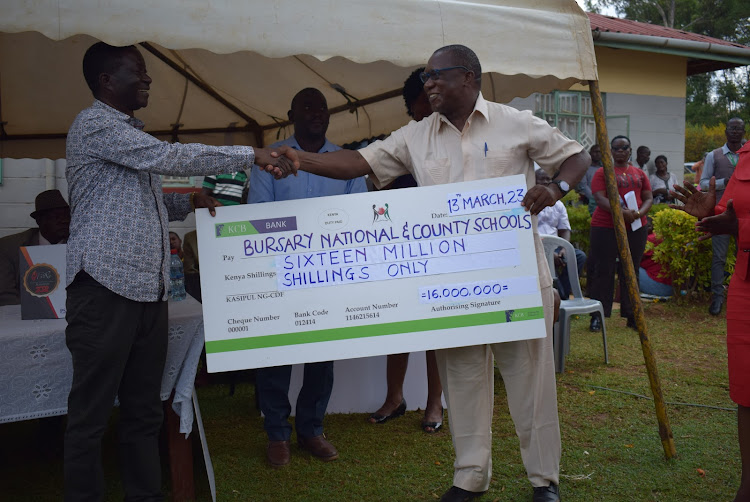 Kasipul MP Ongondo Were and Saye Mixed Secondary School principal Thomas Odongo hold a dummy cheque in Oyugis town on March 13, 2023