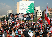 People march as they carry national flags and pictures of some of the victims of last year's Beirut port blast, as Lebanon marks the one-year anniversary of the explosion in Beirut, Lebanon on August 4 2021. 