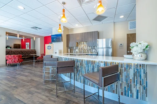 Modern apartment complex communal area with bar stools, a kitchenette, and vibrant interior design.