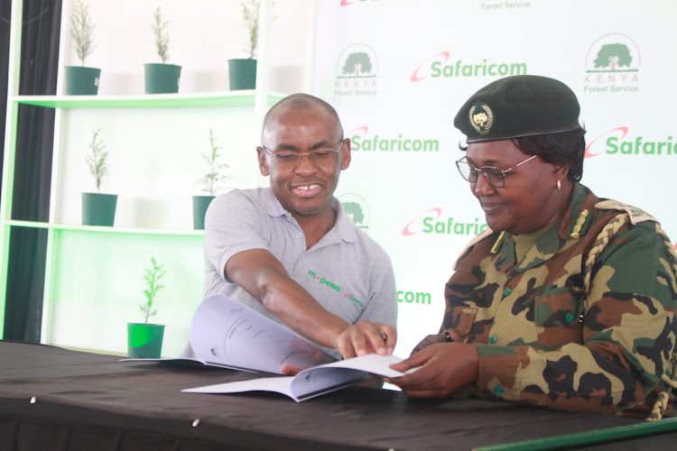 Safaricom CEO Peter Ndegwa and Deputy CCF (Forest Advisory and County liason )Beatrice Mbula signed agreement documents during the marking of the edition off climate action agreement and signing at Kinale forest on April 4, 2023