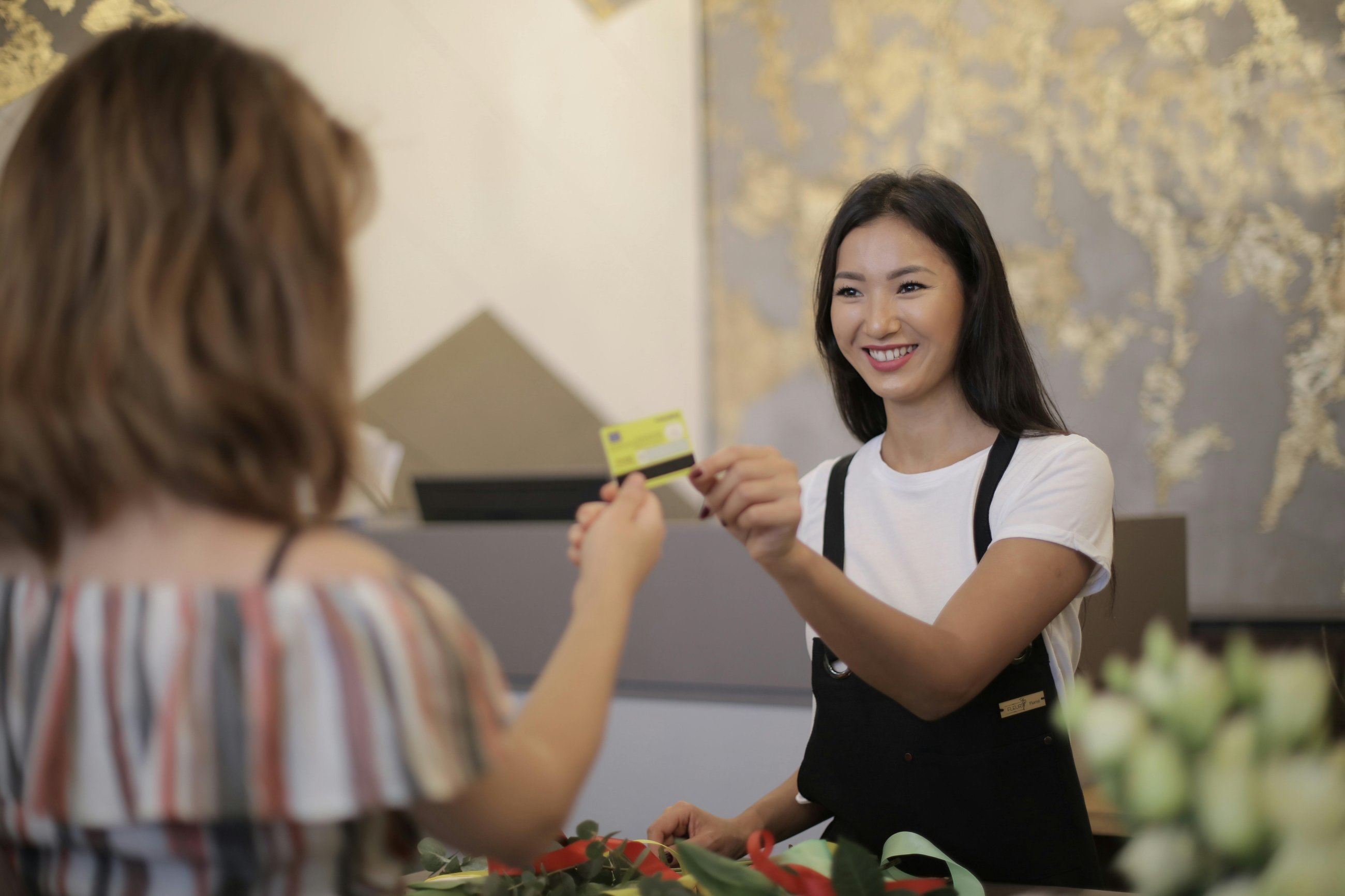 A person behind a desk handing back another person's payment card. 