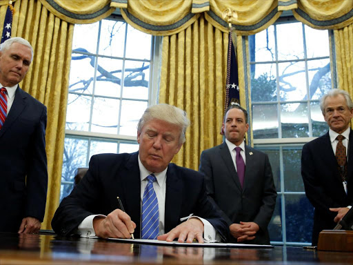 US President Donald Trump, watched by (L-R) Vice President Mike Pence, White House Chief of Staff Reince Priebus, and head of the White House Trade Council Peter Navarro, signs an executive order that places a hiring freeze on non-military federal workers in the Oval Office of the White House in Washington January 23, 2017. /REUTERS