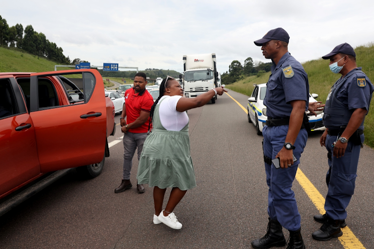 A police officer shields his colleague during an altercation with driving school owners.