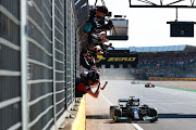 Race winner Lewis Hamilton passes his team celebrating on the pitwall during the F1 Grand Prix of Great Britain at Silverstone on July 18, 2021 in Northampton, England.