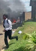 A pupil flees the scene of a fire at a school on KZN's north coast.