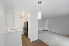 Dining room with entrance to the kitchen and living room. Wood inspired flooring and a pendant light on ceiling.