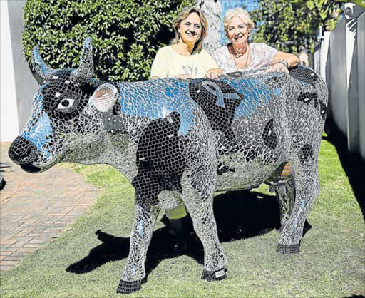 MOOSAIC: Mosaic artist Lorna Gardner, left, and a team of her art students spent eight months beautifying Daisy the cow with thousands of mosaic pieces for the Choc Childhood Cancer Foundation house in Beacon Bay, which is headed by Choc East London regional manager, Debbie Kleinenberg Picture: ALAN EASON