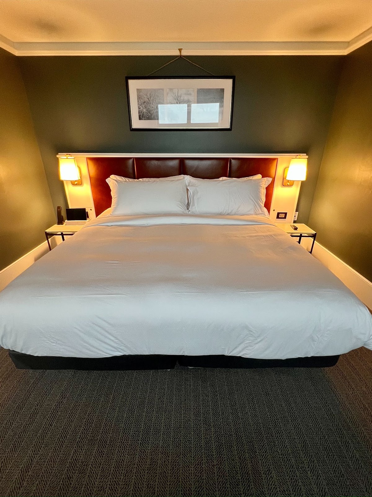 a bed with white sheets and a brown headboard