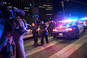 Bystanders stand near pollice baracades following the sniper shooting in Dallas on July 7, 2016. A fourth police officer was killed and two suspected snipers were in custody after a protest late Thursday against police brutality in Dallas, authorities said.