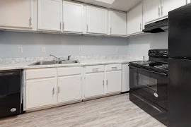 Kitchen with wood-inspired flooring, black appliances, and white cabinets