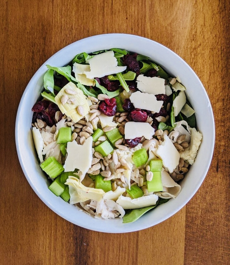 Cranberry Turkey Salad: Roasted turkey, dried cranberries, cheddar cheese, mixed greens, sunflower kernels, artichokes and celery with balsamic & olive oil dressing.