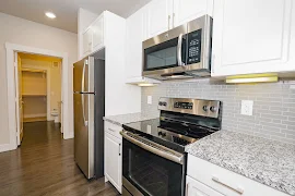 Kitchen featuring stainless steel appliances, tiled backsplash, granite countertops, and white cabinets