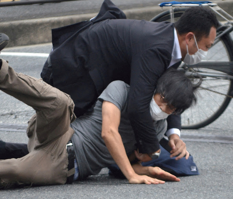 A man, believed to be a suspect shooting former Japanese Prime Minister Abe Shinzo is held by police officers at Yamato Saidaiji Station in Nara, Nara Prefecture on July 8 2022. Picture: REUTERS/JAPAN OUT/YOMIURI SHIMBUN