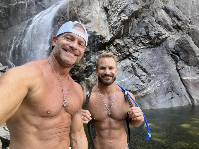 Bruce Jones and Greg Dixxon taking naked selfies outside while near a waterfall