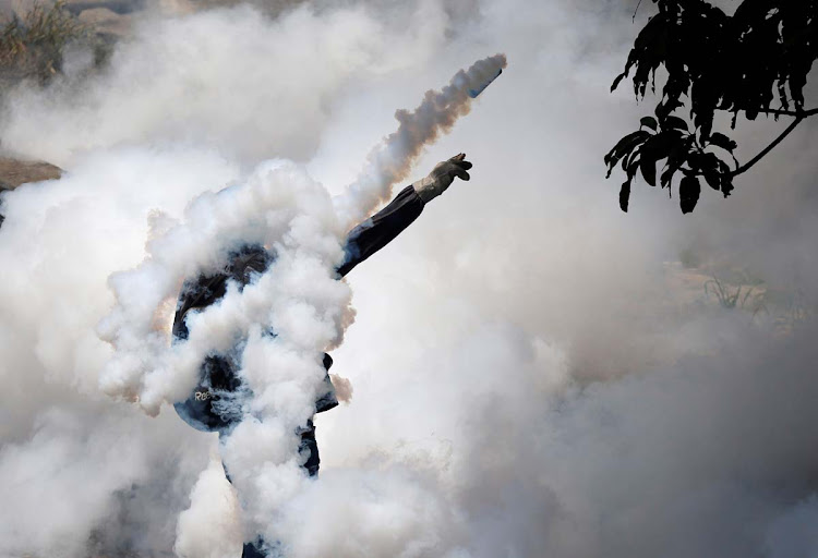 A demonstrator throws back a tear gas grenade while clashing with riot police during the so-called 'mother of all marches' against Venezuela's President Nicolas Maduro in Caracas, Venezuela April 19, 2017.