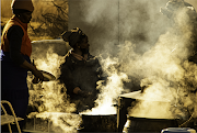 Outside the homestead, a fire burns continually, coals created from the burning tree. Here large round-bellied three-legged cast-iron pots, introduced by early colonialists, cook the vast amounts of food required for the approximate 300 guests and also heat water. Here Rose (left) and Selina Skosana (seated) tend to the cooking. They are sisters to Thabo, the initiate's father.