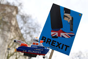 Anti-Brexit protesters hold up a sign and a model prop boat outside Downing Street in London, Britain, February 12, 2019. 