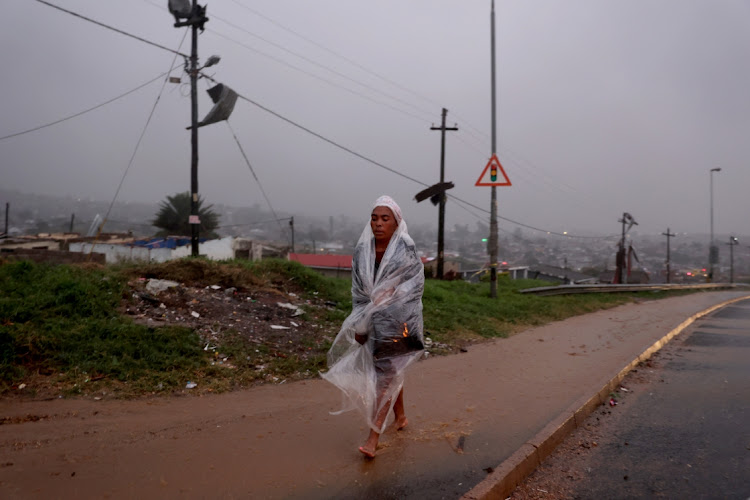 A woman covers herself with a plastic sheet during heavy rain in Inanda, north of Durban, in the aftermath of a tornado.