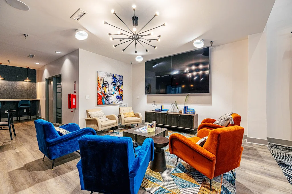 Resident lounge seating area with plush sofa chairs and a mounted television