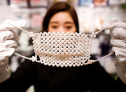 An employee of Cox Co, the operation company of the face-mask speciality shop Mask.com, shows off a luxury face mask made with about 330 pearls which is sellig for one million yen ($9,640), at the shop, amid the coronavirus disease (COVID-19) outbreak, in Tokyo, Japan November 25 2020. 