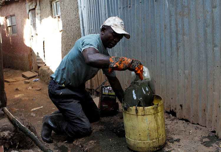 A Kenyan 'frogger' slum dweller Godffrey Ndalo uses a broken plastic jerrycan to empty excrement from a pit latrine in Kibera slum within Nairobi, Kenya on February 19, 2019.