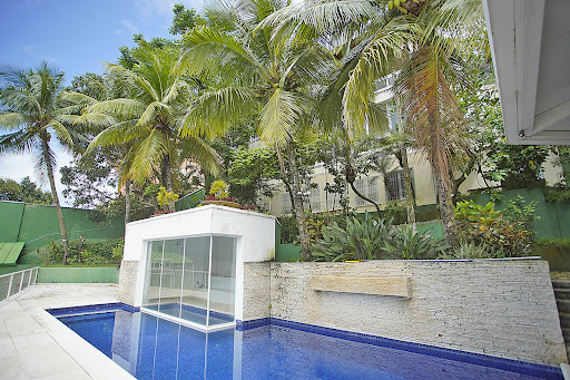 Swimming pool with palm trees and white building in this luxury house for sale in Rio de Janeiro ($1,062,303 - 1,500 m²)