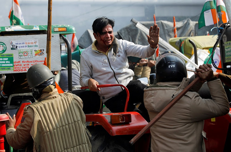 A police officer swings a baton during a protest against farm laws introduced by the government in New Delhi.