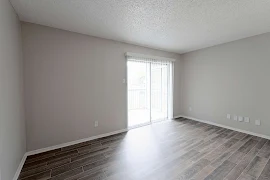 Living area with wood-inspired flooring, sliding patio doors with vertical blinds, and gray walls