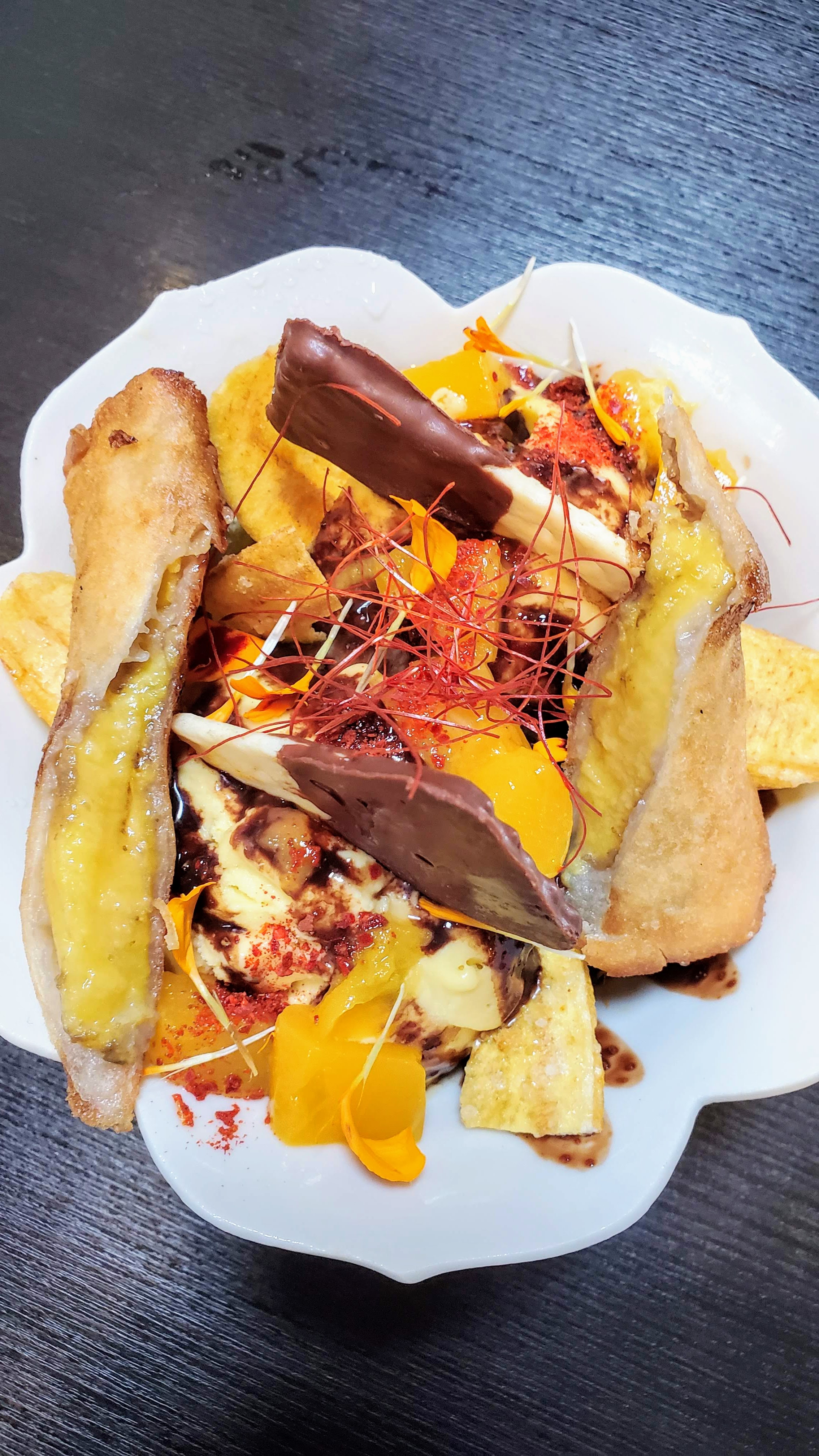 The Ichiza Kitchen  Mango and Chili Ice Cream Sundae with AVIV mango ice cream topped with toastsed coconut flakes, ground chili, mango chunks, chocolate chili sauce and a chocolate coated Filipino soda cracker. Additional option of banana lumpia may be available