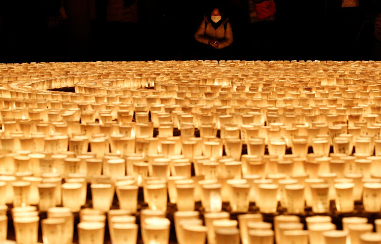 A visitor wearing a protective mask, amid the Covid-19 outbreak, looks at 6,500 candle lights at a ceremony to wish for overcoming the pandemic and good luck in the new year at Hasedera Buddhist temple in Kamakura, south of Tokyo, Japan, on December 31 2021.