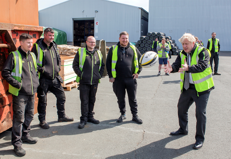 Britain's Prime Minister Boris Johnson catches a rugby ball during his visit at Net World Sports in Wrexham, Wales on April 26