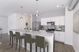 Kitchen with stone countertops, pendant lighting over the island, tile backsplash, white cabinets, and stainless appliances