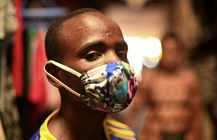 Eugene Amuri, a vendor at the Kimironko market, wears a handmade "kitenge" cloth mask in Kigali, Rwanda, on March 17 2020. WHO updated its guidance to recommend that governments ask everyone to wear fabric face masks in public areas.