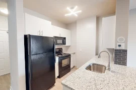 Upscale kitchen with modern lighting, white cabinets, and a tile backsplash