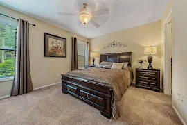 Cozy bedroom with a large bed, nightstands, lamps, ceiling fan, and a framed picture above the bed.