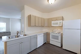 Fully Equipped kitchen with light walls, dark wood inspired floors & neutral cabinets with light counters & appliances