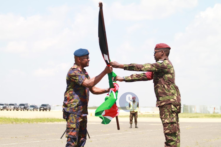 Chief of Defence Forces Francis Ogolla hands over a Kenyan flag to KDF troop from the Democratic Republic of Congo when they arrived at the Embakasi Garrison in Nairobi on December 21, 2023.