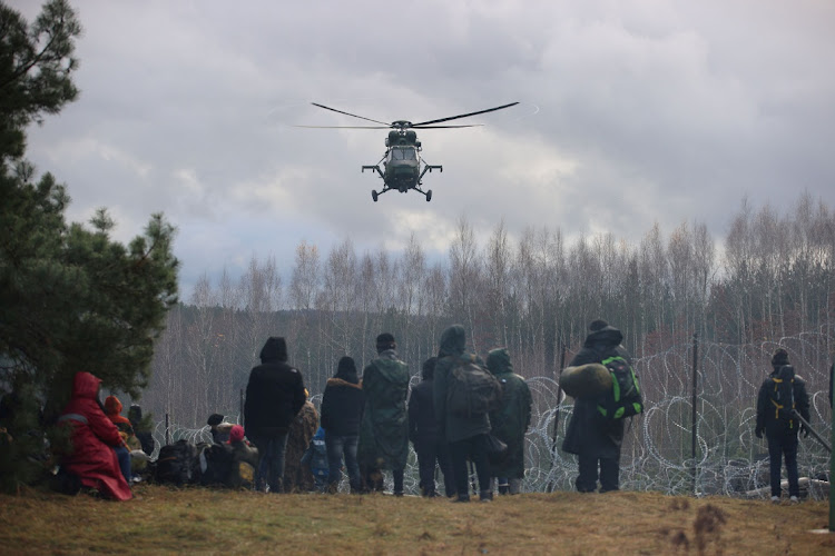 Migrants gather near a barbed wire fence in an attempt to cross the border with Poland in the Grodno region, Belarus, in this November 8 2021 file photo. Picture: REUTERS/BElTA/LEONID SCHEGLOV